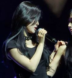 two young women singing into microphones on stage