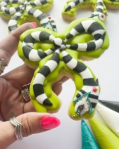 a hand holding a decorated cookie in the shape of an octopus with black and white stripes