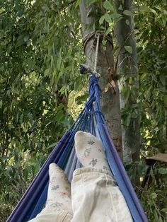 a person laying in a hammock with their feet up on the ground next to some trees