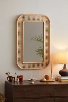 a wooden dresser topped with a mirror next to a lamp