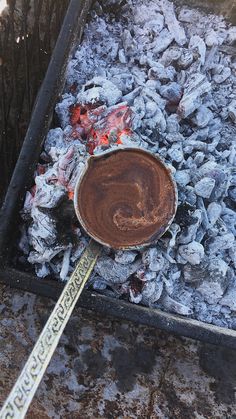 a wooden spoon sitting on top of a pile of charcoal next to a fire pit