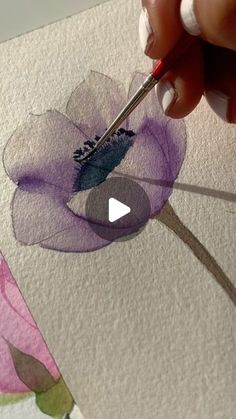 someone is painting flowers with watercolors on paper