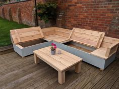 an outdoor seating area with wooden benches and tables on a deck next to a brick wall