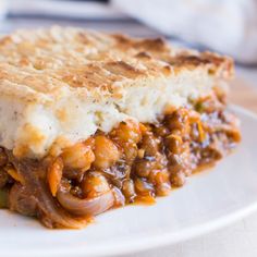 a piece of pie on a plate with cheese and onions in the crust, ready to be eaten