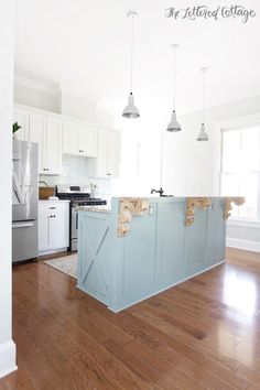 an empty kitchen with white cabinets and wood floors