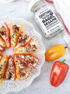 a white plate topped with sliced bell peppers and cheese covered in seasoning next to tomatoes