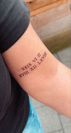 a woman's arm with roman numerals tattooed on the left side of her arm