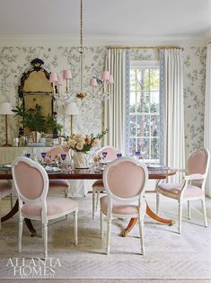 an elegant dining room with pink chairs and floral wallpaper