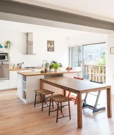 an open kitchen and dining area with wood floors, white walls, and stainless steel appliances