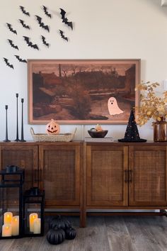 halloween decorations and candles are displayed in front of a painting with bats on the wall