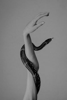 a woman with her arm wrapped around a snake's head, in black and white