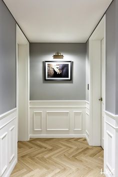 an empty room with wood floors and white walls, framed artwork on the wall above it