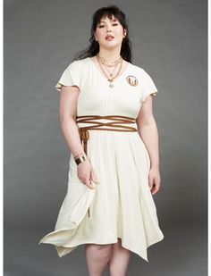 a woman wearing a white dress and brown belt is posing for the camera with her hands in her pockets