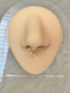 the nose ring has two small curved horns on it's side and is attached to a clear acrylic display case