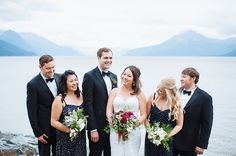 a group of people standing next to each other in front of some water and mountains