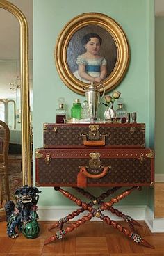 an antique suitcase is sitting in front of a portrait on the wall next to a mirror