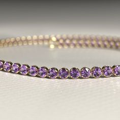 Enhance your bracelet collection with this stunning Amethyst Tennis Bracelet. Handcrafted with care in 14K/18K Gold, its elegant purple stones symbolize the February birthstone. Perfect for stacking, this dainty and versatile piece will elevate your style effortlessly. Whether as a handmade Christmas gift or a treat for yourself, don't miss out on our Cyber Week Sale!𝐅𝐞𝐚𝐭𝐮𝐫𝐞𝐬:• 𝐌𝐚𝐝𝐞 𝐭𝐨 𝐎𝐫𝐝𝐞𝐫• 𝐌𝐞𝐭𝐚𝐥: 𝟏𝟒𝐊 | 𝟏𝟖𝐊• 𝐁𝐚𝐧𝐝 𝐂𝐨𝐥𝐨𝐫𝐬: Rose Gold, Yellow Gold & White Go Formal Round Amethyst Bracelets, Formal Amethyst Round Bracelets, Formal Amethyst Bracelets, Gold Amethyst Bracelets For Formal Occasions, Classic Amethyst Jubilee Bracelet, Purple Round Tennis Bracelet For Formal Occasions, Classic Purple Tennis Bracelet As A Gift, Classic Purple Tennis Bracelet Perfect For Gifts, Classic Purple Tennis Bracelet As Gift