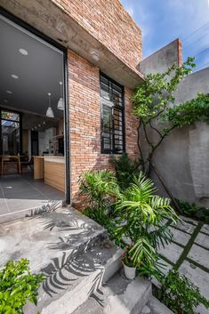 an open door to a brick building with plants in the foreground and stairs leading up to it