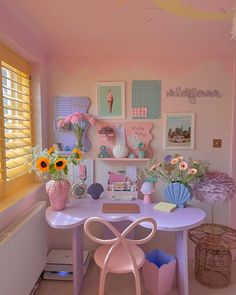 a pink desk with flowers and pictures on the wall