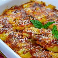 a casserole dish filled with pasta and sauce, garnished with parmesan cheese