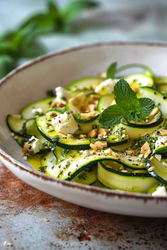 a white bowl filled with cucumbers and feta cheese on top of a table