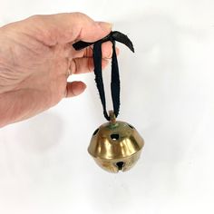 a hand holding a bell ornament on a string