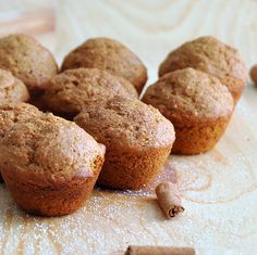 several muffins on a table with cinnamon sticks