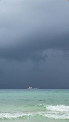 an ocean view with dark clouds in the sky