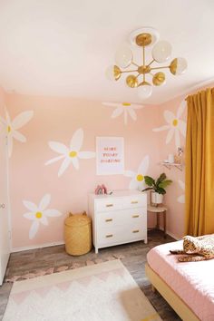 a bedroom with pink walls and white flowers painted on the wall, along with yellow drapes