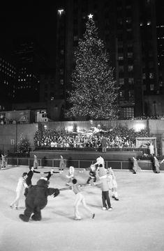 people skating around in front of a christmas tree