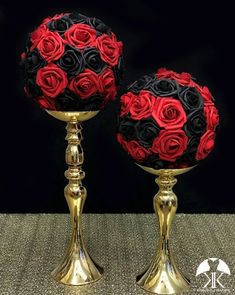 two gold vases with red and black roses on them are sitting side by side