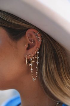 a close up of a person wearing a hat with ear rings and earrings on their ears