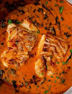 two pieces of fish are in a red sauce