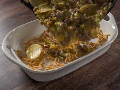 a casserole dish with noodles, meat and vegetables being lifted from the casserole