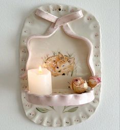 there is a candle and some flowers on the plate with it's holder attached to the wall