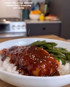 a white bowl filled with rice and meat covered in gravy on top of a wooden table