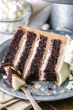 a slice of chocolate cake with white frosting on a plate