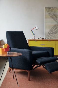 a blue recliner chair sitting on top of a rug next to a wooden table