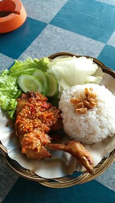 a basket filled with rice, meat and vegetables on top of a checkered table cloth