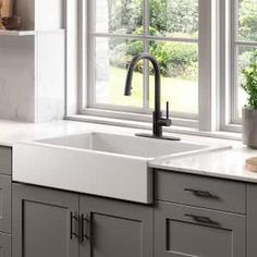 a white kitchen sink sitting under a window next to a potted plant on top of a counter