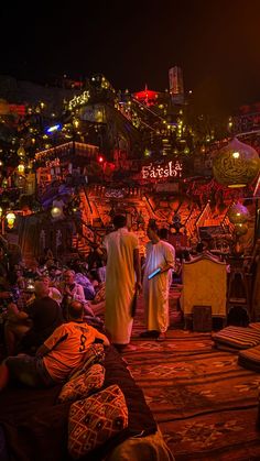 two men standing in the middle of a room filled with lots of furniture and lights