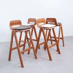 three wooden stools sitting next to each other on top of a gray flooring