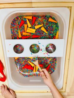 a child is playing with sprinkles and spoons in a play kitchen