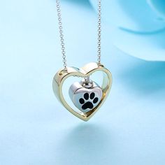 a heart shaped pendant with a dog's paw inside it on a blue background