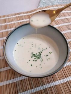 a spoon pouring milk into a bowl on top of a place mat with a checkered table cloth