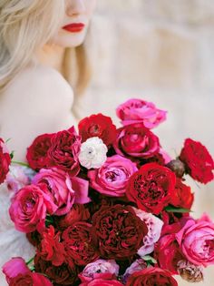 a woman holding a bouquet of red and pink flowers