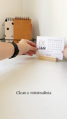 two hands holding up a calendar on top of a table