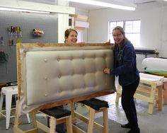 two women are smiling and holding up a piece of furniture that is being made out of plywood