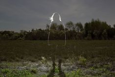 an image of a person standing in the middle of a field at night with long white hair