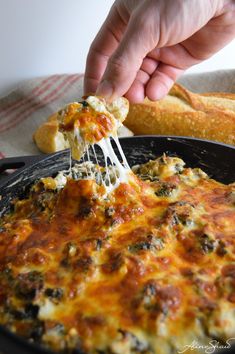 a person scooping cheese from a skillet with breadsticks in the background